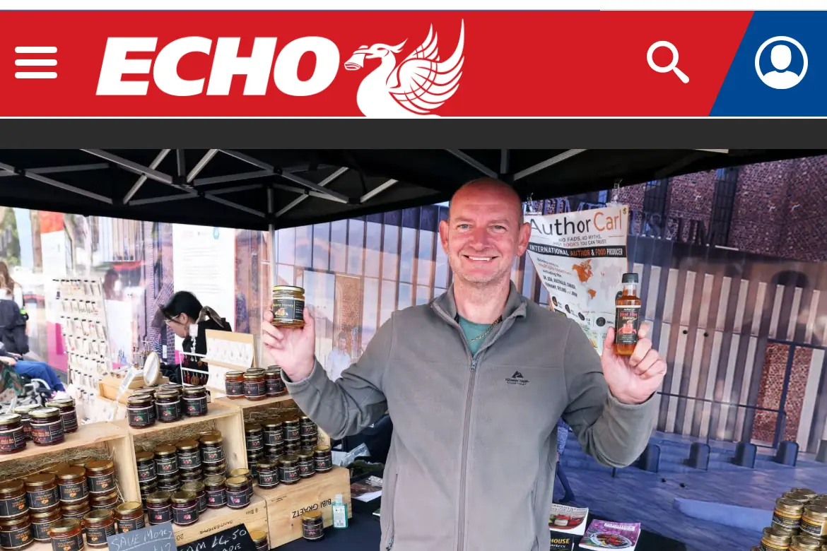 Carl Williams holding two jars of Author Carl honey at his Royal Albert Dock market stall, as featured by the Liverpool Echo